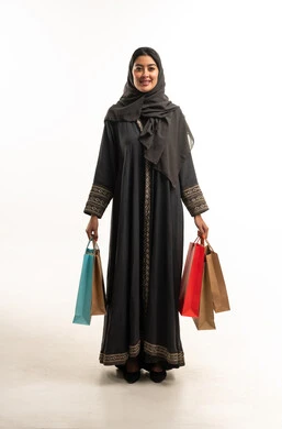 امرأة سعودية بعباءة تحمل حقائب تسوق ملونة