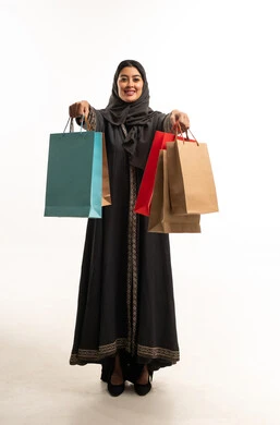 امرأة سعودية بالعباءة تحمل حقائب تسوق ملونة