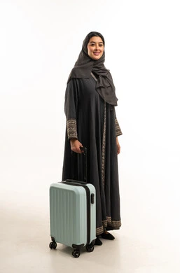 امرأة سعودية بالعباءة مع حقيبة سفر زرقاء