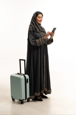 Saudi Woman with Suitcase Using Smartphone for Travel