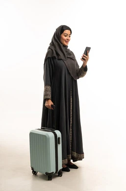 امرأة سعودية مع حقيبة سفر وهاتف ذكي