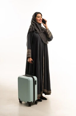 امرأة إماراتية مع حقيبة سفر تتحدث بالهاتف المحمول