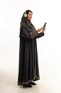 Saudi Woman in Abaya Using Smartphone with Headphones