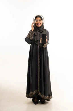 امرأة سعودية بالعباءة تستخدم السماعات والهاتف الذكي