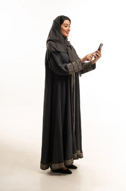 امرأة سعودية بالعباءة تستخدم الهاتف المحمول