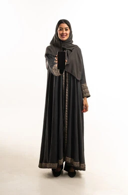 امرأة سعودية بالعباءة تحمل هاتف ذكي في الاستوديو