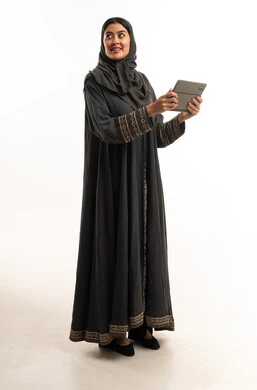 امرأة سعودية بعباءة سوداء تحمل جهاز لوحي في الاستوديو