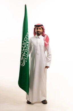 رجل سعودي يمسك العلم الوطني على خلفية بيضاء