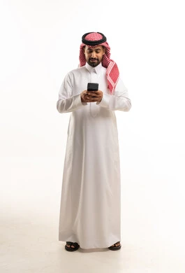 رجل سعودي بالثوب التقليدي يستخدم الهاتف الذكي بخلفية بيضاء