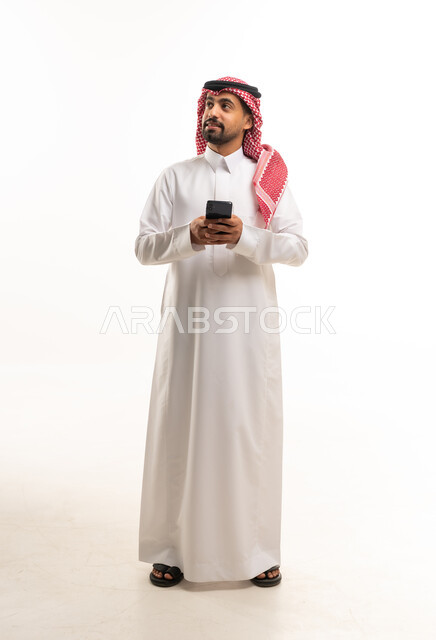 Saudi Man in Traditional Thobe Using Smartphone