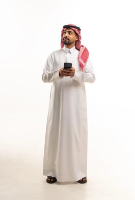 رجل سعودي بالثوب التقليدي يستخدم الهاتف الذكي