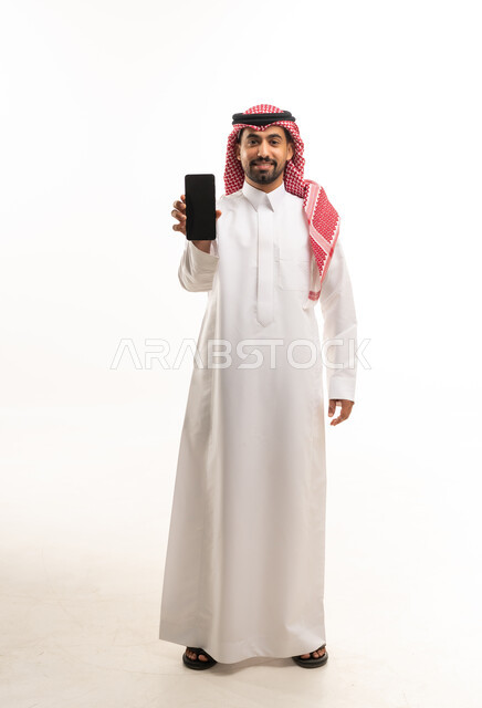 رجل سعودي يحمل هاتف ذكي على خلفية بيضاء