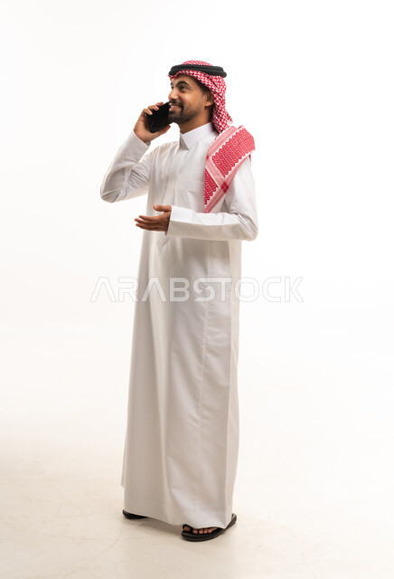 رجل سعودي بالثوب التقليدي يستخدم الهاتف الذكي