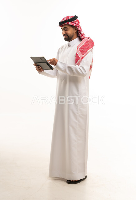 Saudi Man in Traditional Thobe Using Tablet