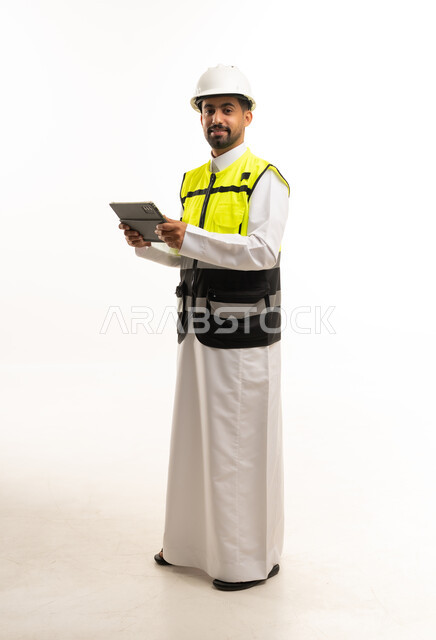 مهندس سعودي يرتدي معدات السلامة ويحمل جهاز لوحي