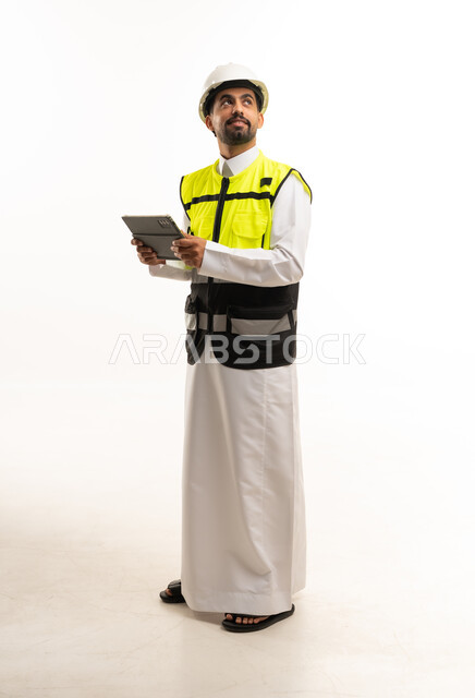 مهندس سعودي بالثوب وسترة السلامة مع جهاز لوحي