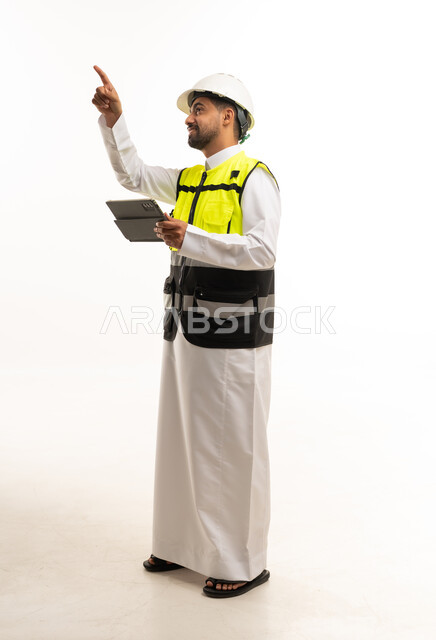 مهندس سعودي يرتدي سترة السلامة ويحمل جهاز لوحي