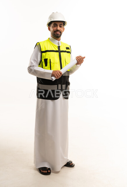 مهندس سعودي بالثوب وسترة السلامة يحمل مخططاً هندسياً