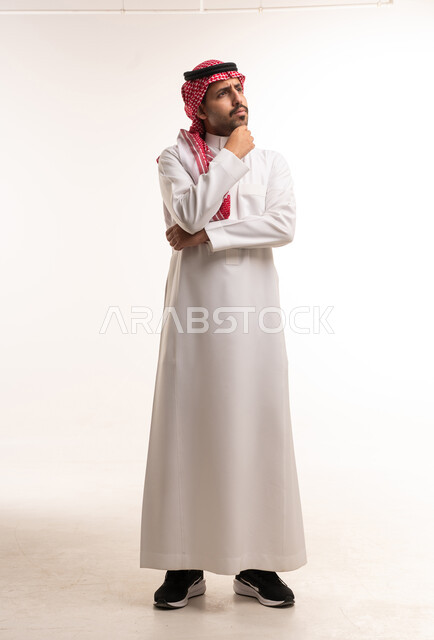 رجل سعودي يرتدي الزي التقليدي في وضعية تفكير وتأمل