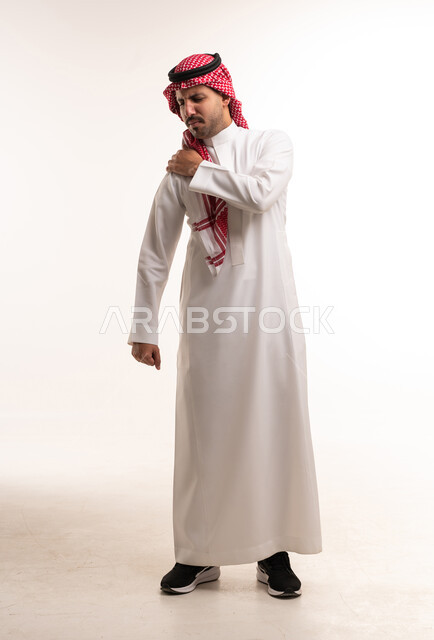 رجل سعودي بالثوب التقليدي يعاني من ألم في الكتف