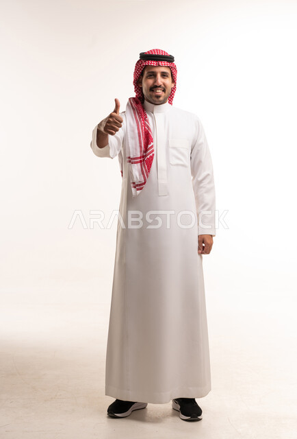 رجل سعودي بالثوب التقليدي يبتسم ويشير بالإبهام للأعلى
