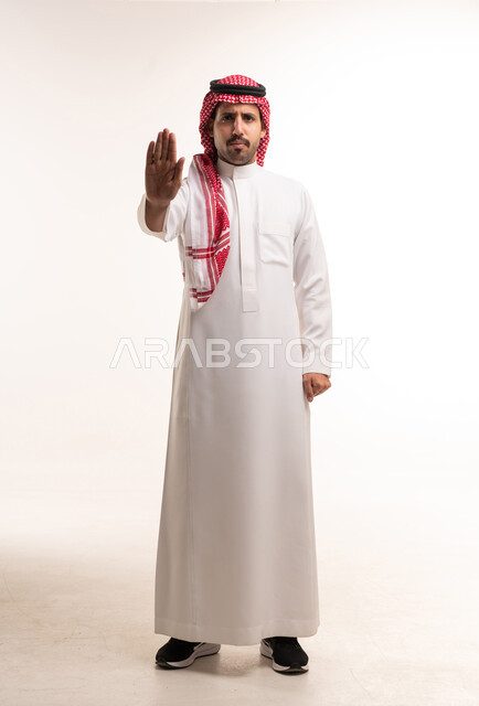 رجل سعودي بالثوب التقليدي يقوم بإشارة التوقف بيده