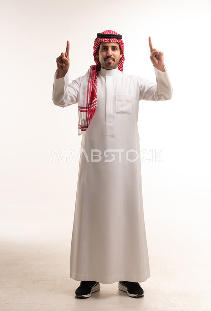 رجل سعودي بالثوب التقليدي يشير للأعلى بخلفية بيضاء