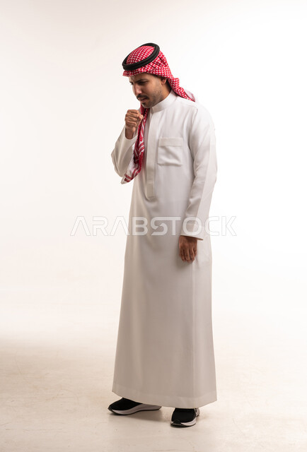 رجل سعودي بالثوب التقليدي يسعل في استوديو