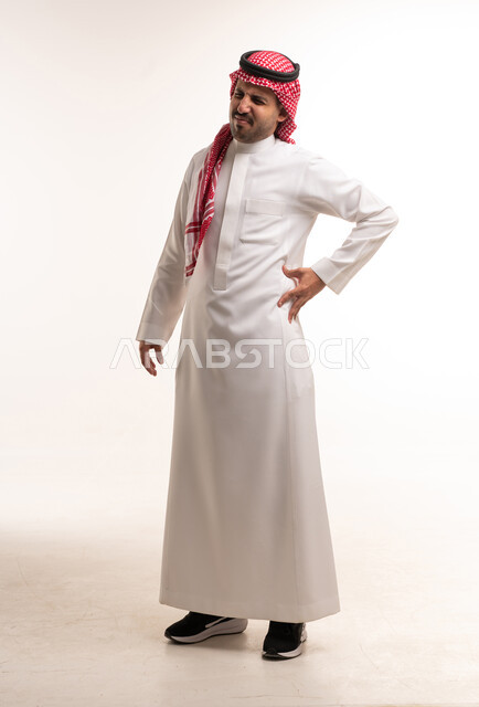 رجل سعودي بالثوب التقليدي يعاني من ألم الظهر