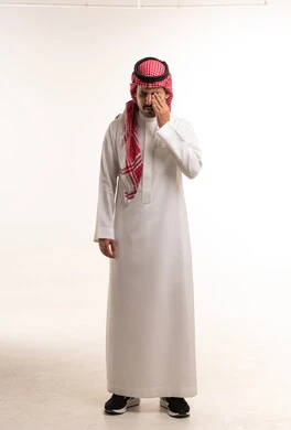 رجل سعودي بالزي التقليدي يفرك عينه في استوديو