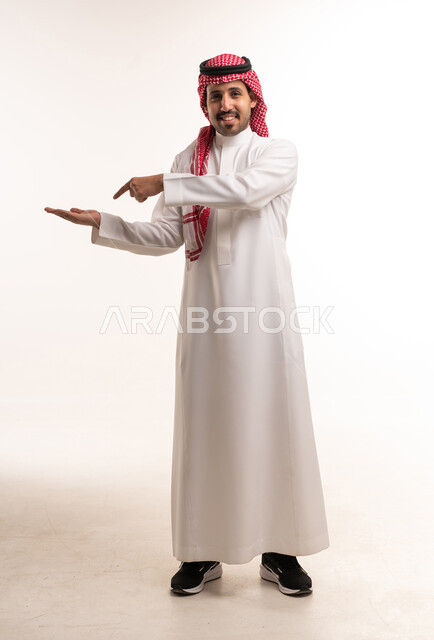 رجل سعودي بالزي التقليدي يشير بيده على خلفية بيضاء