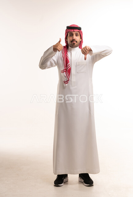 رجل سعودي يرفع إبهامه للأعلى وللأسفل في استوديو
