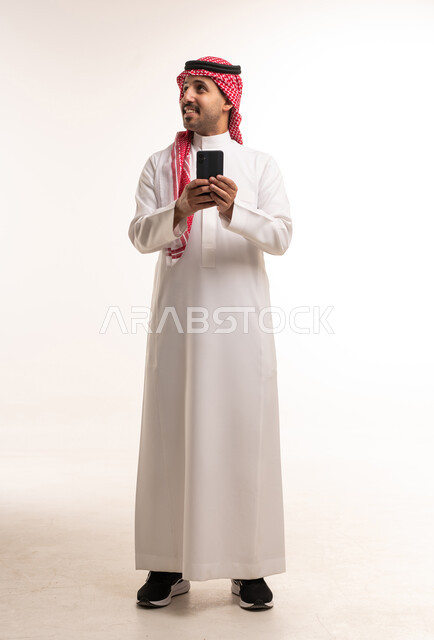 Saudi Man in Thobe and Shemagh Holding Smartphone