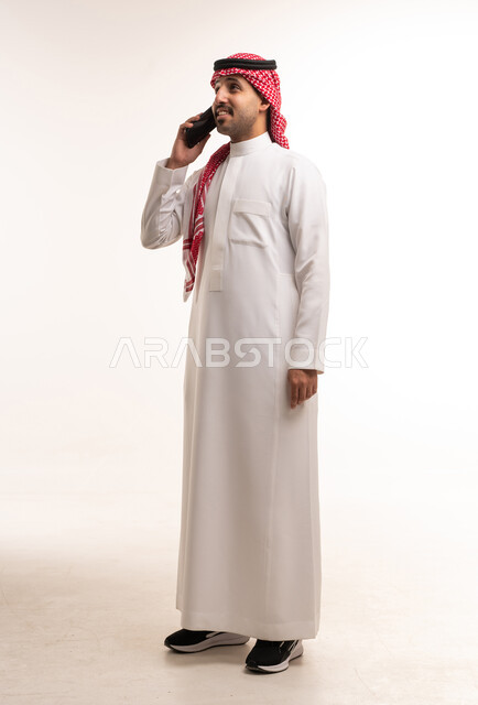 رجل سعودي بالزي التقليدي يتحدث عبر الهاتف الذكي