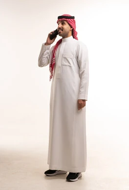Saudi Man in Traditional Thobe Talking on Smartphone