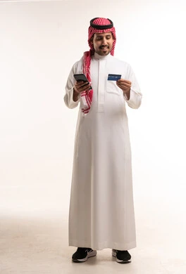 رجل سعودي بالثوب يحمل بطاقة ائتمانية وهاتف ذكي