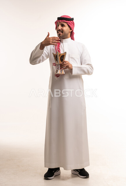 رجل سعودي بالزي التقليدي يحمل مبخرة بخور خشبية