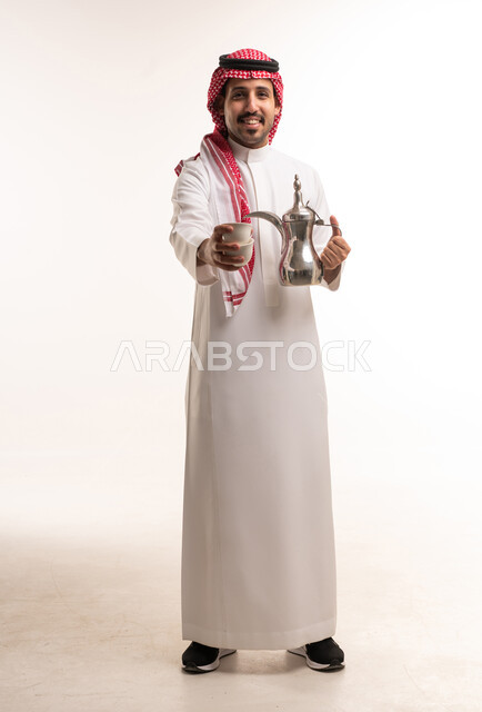 رجل سعودي بالزي التقليدي مع دلة القهوة العربية