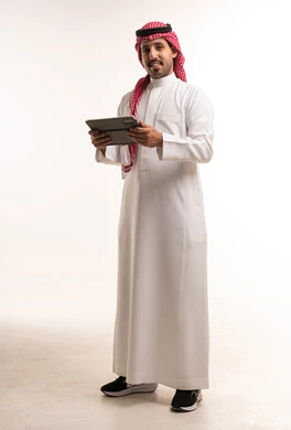 رجل سعودي بالثوب التقليدي يمسك جهاز لوحي رقمي