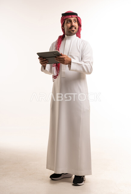 رجل سعودي بالزي التقليدي يستخدم جهاز لوحي