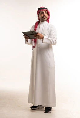 رجل سعودي بالزي التقليدي يستخدم جهاز لوحي