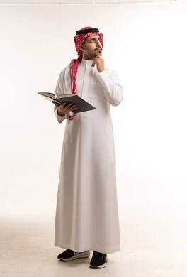 رجل سعودي بالزي التقليدي يمسك كتاباً