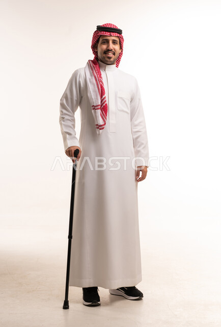 رجل سعودي بالزي التقليدي مع عصا للمشي