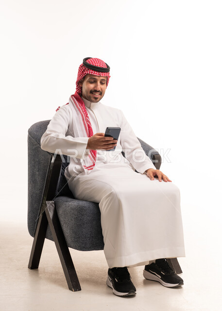 رجل سعودي بالزي التقليدي يستخدم الهاتف في الاستوديو