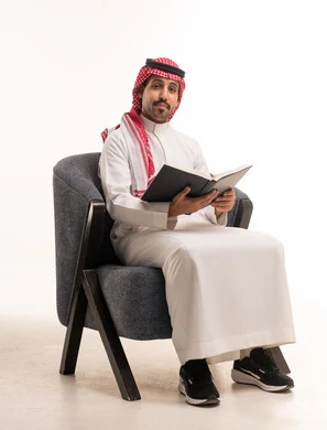 رجل سعودي بالزي التقليدي يقرأ كتاباً في الاستوديو
