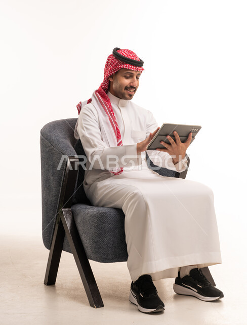 رجل سعودي بالزي التقليدي يستخدم جهاز لوحي في الاستوديو