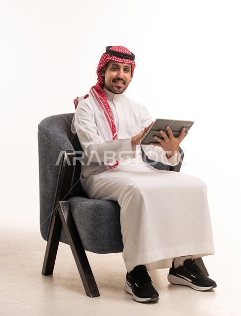 رجل سعودي يستخدم جهاز لوحي بخلفية بيضاء