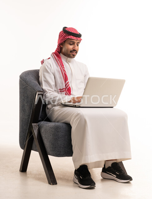 رجل سعودي يستخدم الحاسوب المحمول بالزي التقليدي