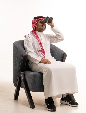 Saudi Man in Traditional Thobe Using Binoculars in Studio