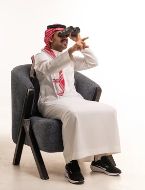 Saudi Man in Traditional Thobe Using Binoculars Indoors